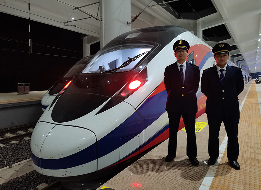 劉銀能（右一）與中國師父鄔俊鴻在動車組前合影。受訪者供圖