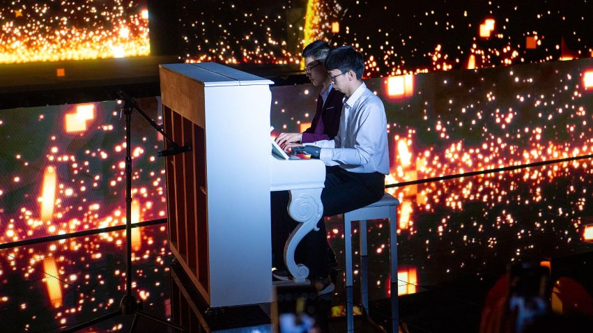 智能仿生手使用者古月與少年鋼琴家舒海峰合奏。主辦方供圖